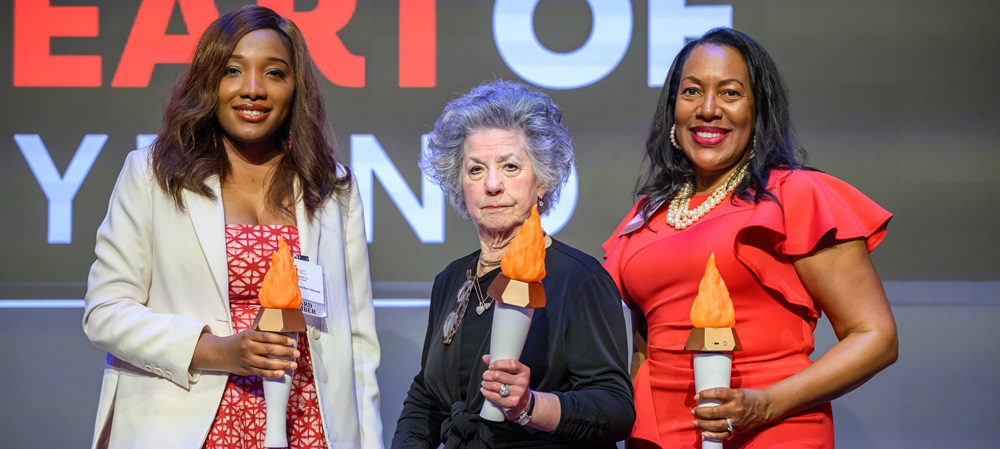 Three women on stage holding lit torches.
